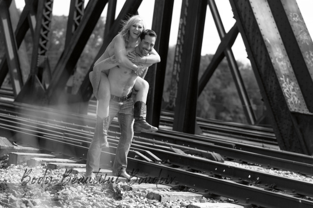 Couple riding piggy back on railroad track